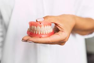 dentist holding dentures in Crown Point and Whiting