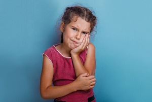 A young girl holding her cheek in pain
