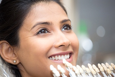 A woman having a shade guide used to match her tooth color