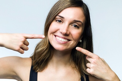 A young woman pointing to her smile