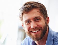 Man with dental implants smiling in front of window