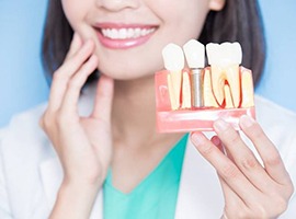 dentist holding a dental implant in a model of part of the jaw 