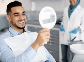 Patient smiling at reflection in handheld mirror