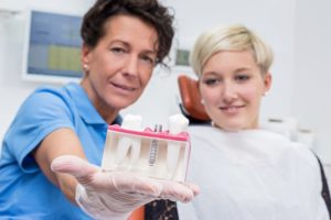 dentist showing patient implant model