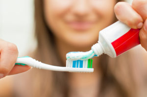 woman applying toothpaste to toothbrush 