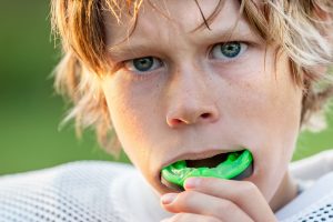 Young football player inserting mouthguard