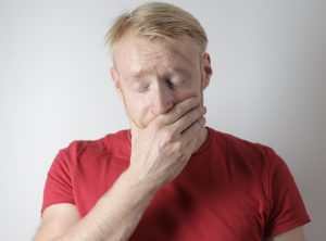 Man in pain with hand over mouth